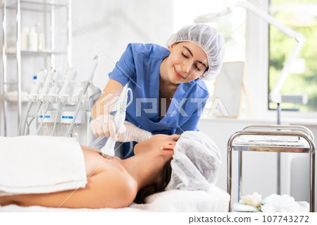 Female aesthetician administering ultrasound procedure on decollete area to woman Female aesthetician administering ultrasound procedure on decollete area to woman 107743272