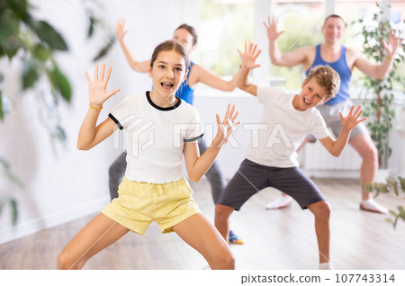 Happy preteen boy and girl practicing dance movements with their parents 107743314