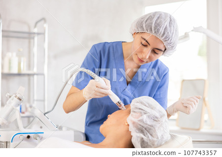 Aesthetician administering facial procedure on woman using ion bubble attachment Aesthetician administering facial procedure on woman using ion bubble attachment 107743357