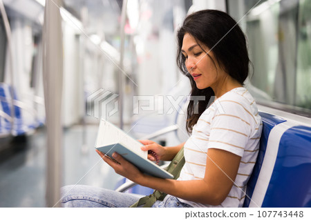 Woman reading book in subway train 107743448