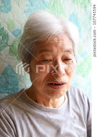一位老年婦女坐在斜躺護理床上的臉部特寫 一位老年婦女坐在斜躺護理床上的臉部特寫 107743594