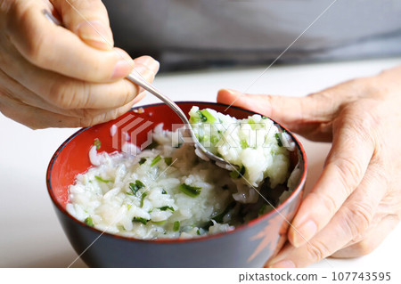 用湯匙將粥放在碗裡的手的特寫 107743595
