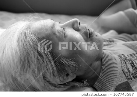 躺下在護理床上休息的老年婦女 躺下在護理床上休息的老年婦女 107743597