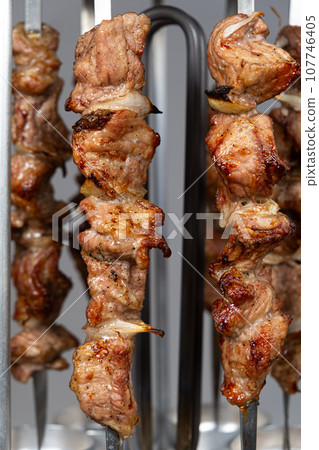 Cooking pork meat in an electric kebab maker on vertical skewers Cooking pork meat in an electric kebab maker on vertical skewers 107746405