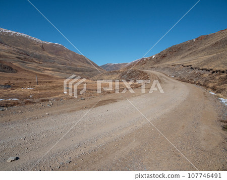Dirt road uphill. Dangerous narrow dirt mountain road through the hills to a high-altitude village. Altai region. 107746491