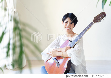 woman holding a guitar in the room 107747398