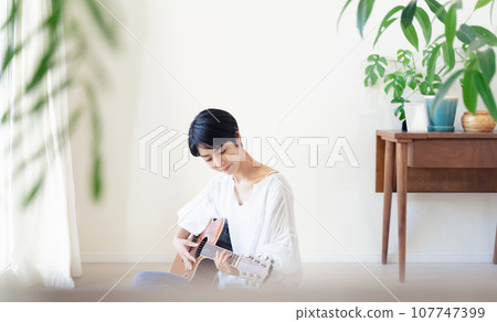 woman holding a guitar in the room 107747399