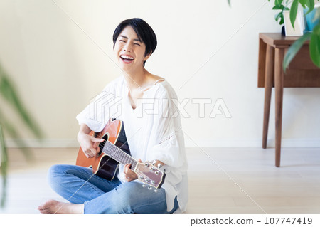 woman holding a guitar in the room 107747419