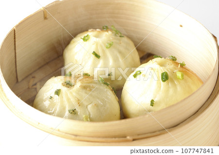A photo of piping hot xiaolongbao steamed in a steamer against a white background 107747841