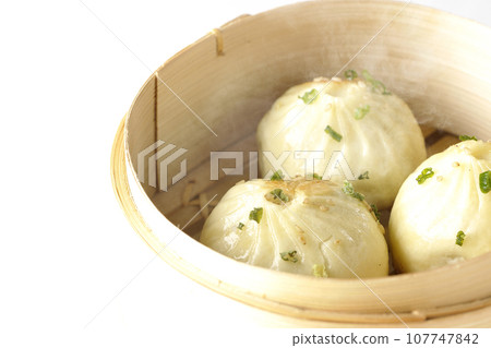A photo of piping hot xiaolongbao steamed in a steamer against a white background A photo of piping hot xiaolongbao steamed in a steamer against a white background 107747842