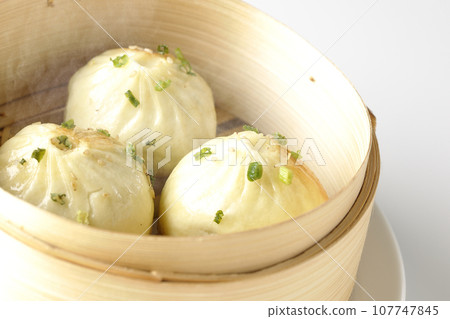 A photo of piping hot xiaolongbao steamed in a steamer against a white background A photo of piping hot xiaolongbao steamed in a steamer against a white background 107747845