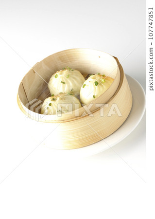 A photo of piping hot xiaolongbao steamed in a steamer against a white background 107747851