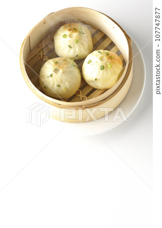 白色背景下蒸籠裡蒸著滾燙的小籠包的俯視照片 107747877