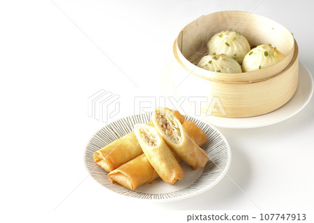 Fried spring rolls and piping hot xiao long bao in a steamer basket Fried spring rolls and piping hot xiao long bao in a steamer basket 107747913