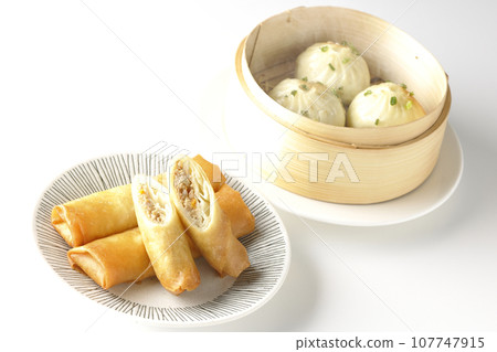 Fried spring rolls and piping hot xiao long bao in a steamer basket 107747915