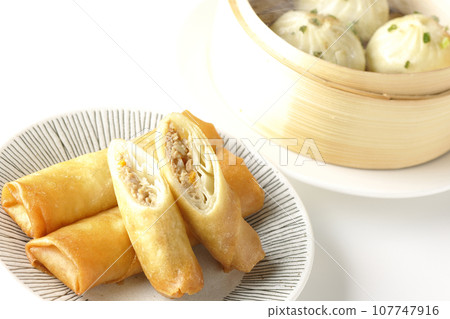 Fried spring rolls and piping hot xiao long bao in a steamer basket 107747916