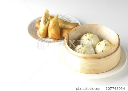 Piping hot xiaolongbao and fried spring rolls in a steamer basket 107748034