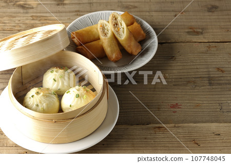 Piping hot xiaolongbao and fried spring rolls in a steamer basket Piping hot xiaolongbao and fried spring rolls in a steamer basket 107748045
