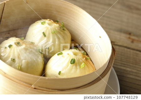 熱氣騰騰的蒸餃子放入蒸籠裡 熱氣騰騰的蒸餃子放入蒸籠裡 107748129