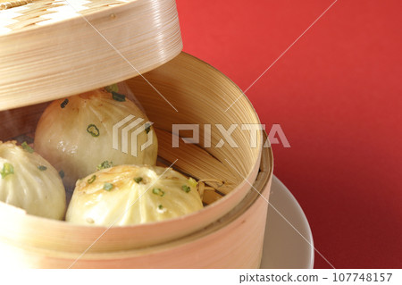 熱氣騰騰的蒸餃子放入蒸籠裡 熱氣騰騰的蒸餃子放入蒸籠裡 107748157