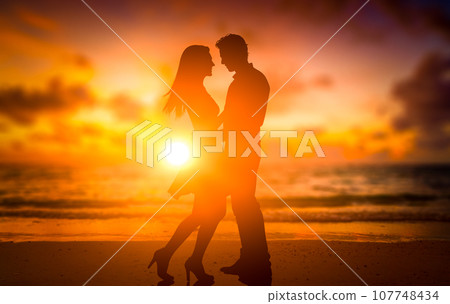 silhouettes of young couple of lovers at sunset on the beach. romance, relationships, love. Holiday romance, honeymoon 107748434