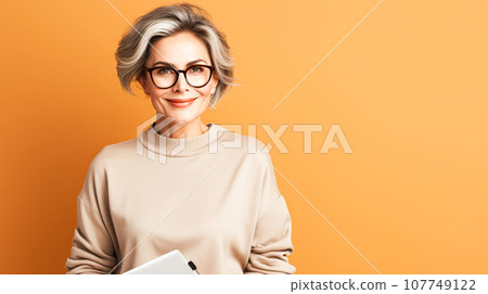 Confident modern adult woman with gray hair stands against bright orange wall, smiles Confident modern adult woman with gray hair stands against bright orange wall, smiles 107749122
