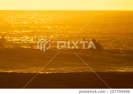 People swimming in the sea at bright orange sunset 107749496