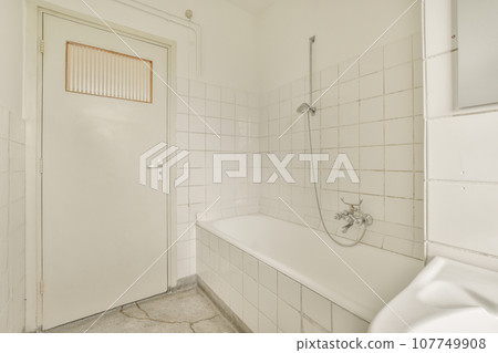 a bathroom with white tiles on the walls, and an open shower stall in the corner next to the bathtub a bathroom with white tiles on the walls, and an open shower stall in the corner next to the bathtub 107749908