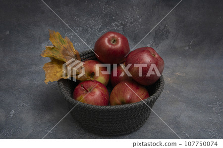 Red juicy apples in a gray basket Red juicy apples in a gray basket 107750074