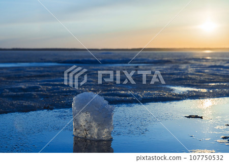 Winter landscape with frozen lake. Ice cube lays in a sunlight Winter landscape with frozen lake. Ice cube lays in a sunlight 107750532