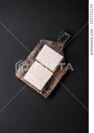 Delicious fresh ricotta cheese cut into slices with vegetables, salt and spices Delicious fresh ricotta cheese cut into slices with vegetables, salt and spices 107751274