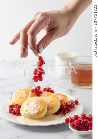 Cottage cheese pancakes, syrniki, ricotta fritters with fresh berries and sour cream on white marble background. Healthy and delicious breakfast, high key Cottage cheese pancakes, syrniki, ricotta fritters with fresh berries and sour cream on white marble background. Healthy and delicious breakfast, high key 107751822