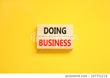 Doing business symbol. Concept words Doing business on beautiful wooden block. Beautiful yellow table yellow background. Business, motivational Doing business concept. Copy space. 107752218