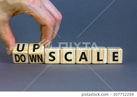 Upscale or downscale symbol. Concept words Upscale or Downscale on wooden cubes. Beautiful grey table grey background. Businessman hand. Business upscale or downscale concept. Copy space. 107752289