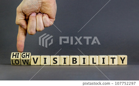 High or low visibility symbol. Concept words High visibility and Low visibility on wooden cubes. Businessman hand. Beautiful grey background. Business high or low visibility concept. Copy space. 107752297
