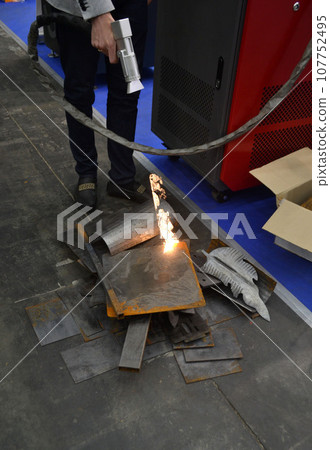 Laser metal cleaning. A man using laser metal cleaning machine to clean a metal surface from rust. Worker cleaning metal from coating by laser. Steel laser clean technologies. New modern technology Laser metal cleaning. A man using laser metal cleaning machine to clean a metal surface from rust. Worker cleaning metal from coating by laser. Steel laser clean technologies. New modern technology 107752495