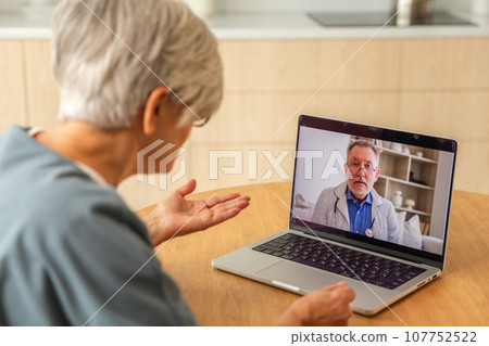 Senior man doctor expert examining older senior woman online. Old woman lady patient and doctor talk on video call have consultation with laptop. Medicine healthcare medical checkup. Online doctor 107752522