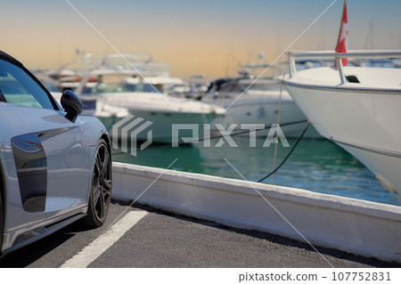Luxury sports car on the background of yachts. Luxury sports car on the background of yachts. 107752831