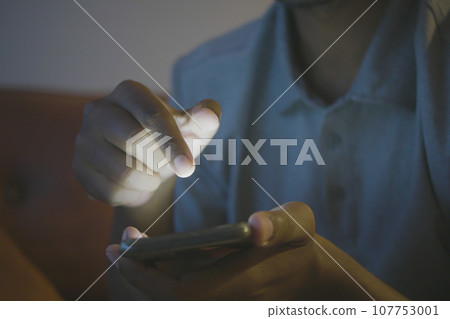 Close up of man's hand using smart phone at night  107753001