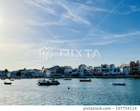 Canal de Tavira . Small boat cruising tranquil green river. 107754114