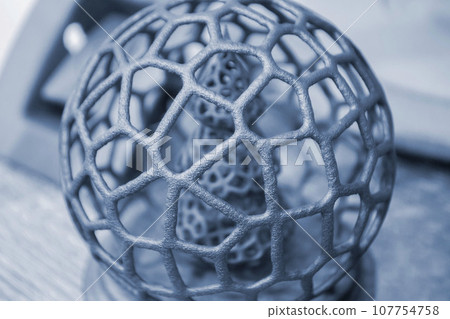 Abstract model Christmas tree in mesh ball printed on 3D printer from polyamide powder close-up. Technology Multi Jet Fusion, MJF. Three-dimensional model created on 3D printer from powder plastic Abstract model Christmas tree in mesh ball printed on 3D printer from polyamide powder close-up. Technology Multi Jet Fusion, MJF. Three-dimensional model created on 3D printer from powder plastic 107754758