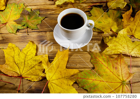 Cup of coffee and autumn maple leaves on wooden table. Autumn concept Cup of coffee and autumn maple leaves on wooden table. Autumn concept 107758280