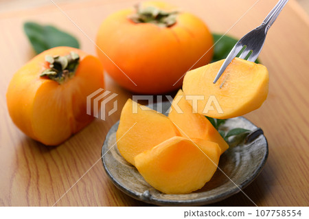 A very sweet taste of autumn Picking up persimmons on a plate with a fork Fruit (table back) Persimmon fruit Oysters 107758554