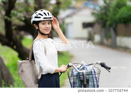 年輕女子站在自行車旁邊,手放在頭盔上 年輕女子站在自行車旁邊,手放在頭盔上 107758744