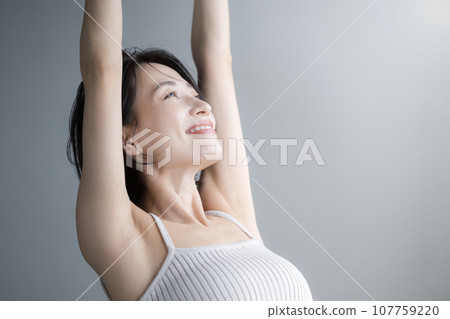 一個女人在早晨的陽光下伸展雙臂的特寫 107759220