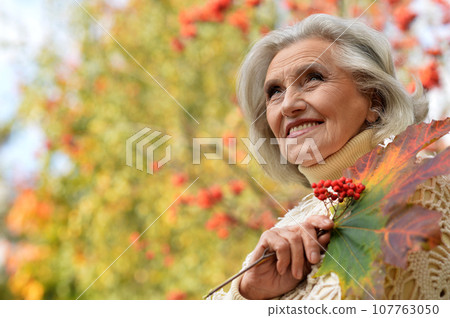 Senior woman walking in the park in autumn.  107763050