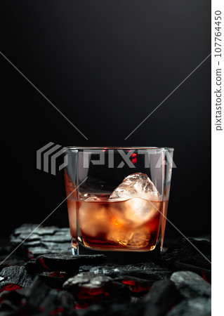 Whiskey with ice in dampened glass. Whiskey with ice in dampened glass. 107764450