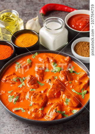 Chicken tikka masala is a dish consisting of roasted marinated chicken chunks in a spiced creamy sauce closeup on the plate. Vertical Chicken tikka masala is a dish consisting of roasted marinated chicken chunks in a spiced creamy sauce closeup on the plate. Vertical 107764759