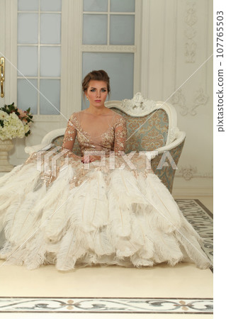 Elegant attractive model woman in perfect evening gown resting on armchair in luxurious interior 107765503