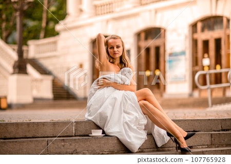 Woman city blanket. Morning in the big city. A blonde woman in a white blanket is enjoying in the city center. Photographed for social media 107765928
